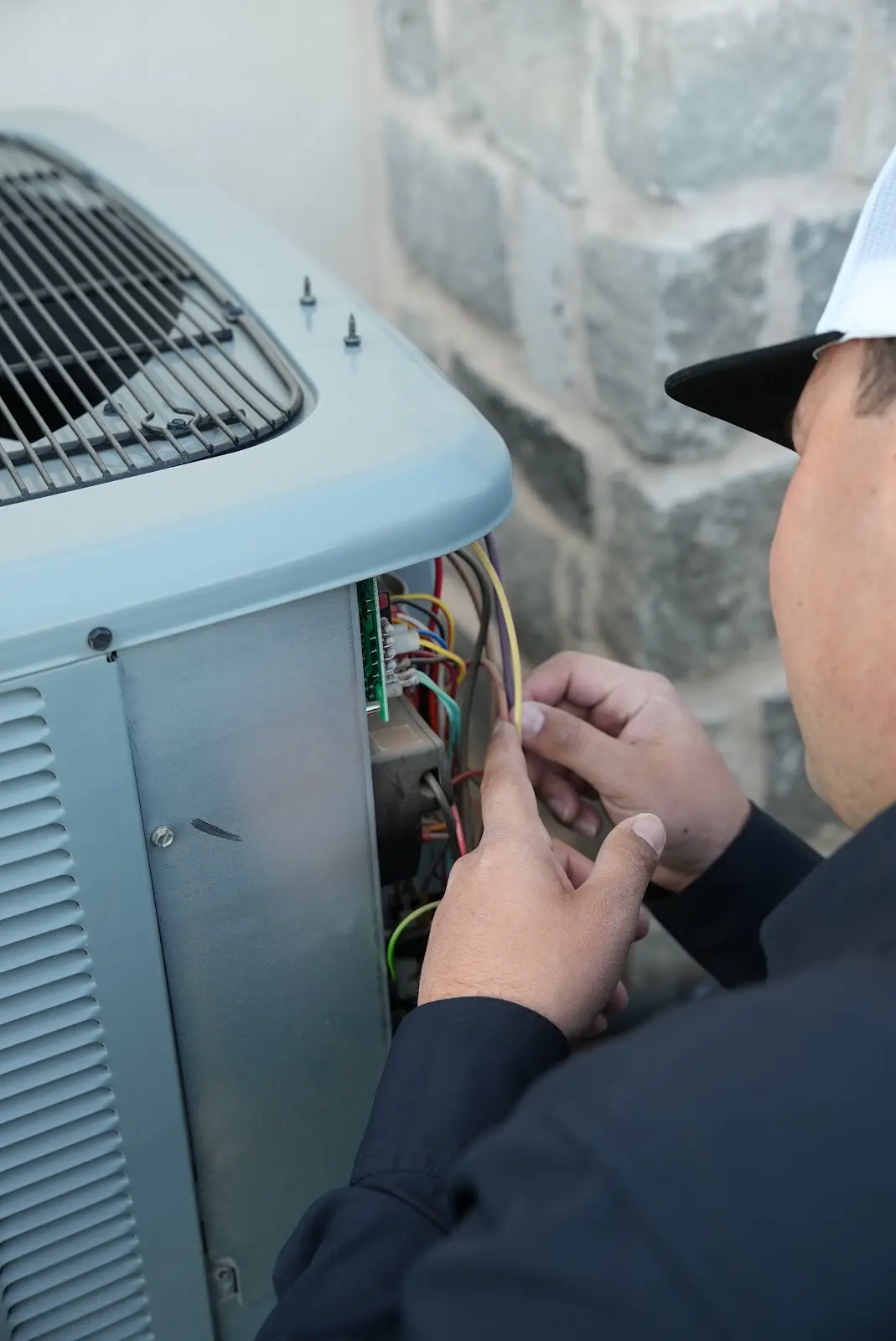 Technician working on the wiring of an outdoor HVAC unit